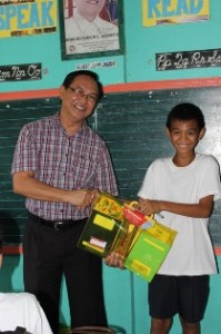 JD Pamana Pres. Mr. Dan smiles to the camera while giving a grade 6 his supplies